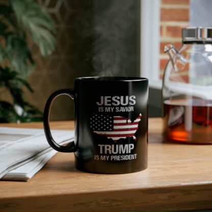 Jesus is My Savior Trump is My President Mug in black on a wooden office desktop.